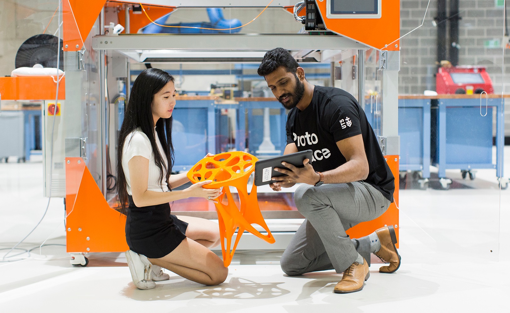 Two students inspect a 3D printed stool